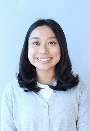 Dr. Taylor Truong smiling for a professional photo in front of a white background. She has on a grey cardigan and white shirt.