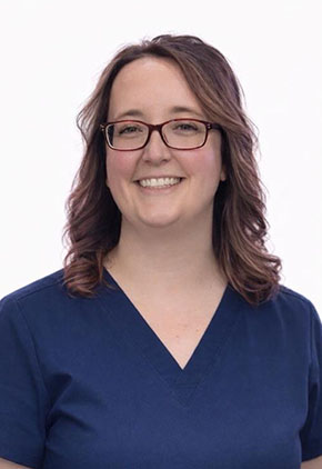 Dr. Robyn Jolly smiles for a professional headshot in front of a white background. She is wearing navy scrubs.