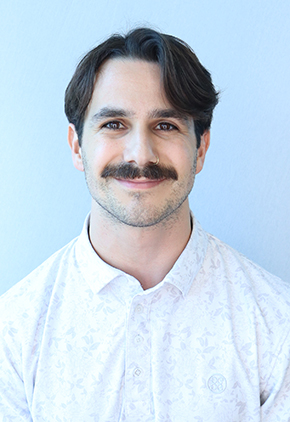 Dr. Benjamin Morales smiles for a professional headshot in front of a white backdrop. He's wearing a white dress shirt with a faint floral pattern.