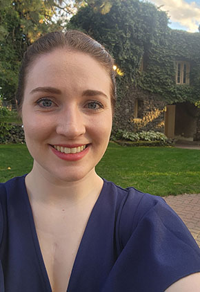 Dr. Winter Herron smiles outside in front of an older European home. She is wearing a navy dress.