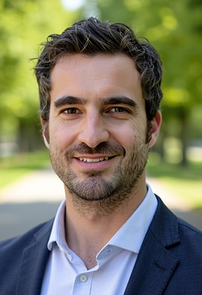 Dr. James Wood smiles outside for a professional headshot. He is wearing a light blue button-up shirt and a navy sport coat.