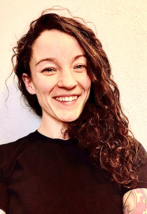 Dr. Amanda Doran smiles outside against a tan wall. She is wearing a black top.