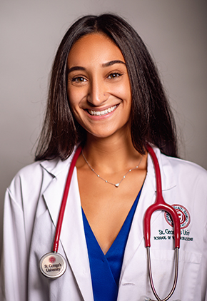 Dr. Victoria Iarrobino smiles for her Veterinary School photo. She is wearing a blue top, her school whitecoat and has a stethoscope around her neck.