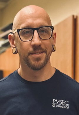 Dan Kavanaugh smiles in the patient care area of our hospital. He is wearing a navy BluePearl t-shirt.