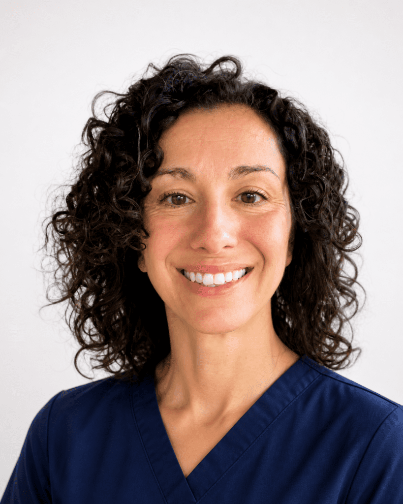 Dr. Renessa Linstromberg smiles for a professional headshot in front of a white background. She is wearing navy scrubs.