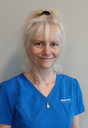 Dr. Beatrix Nanai smiles for a headshot in front of a light tan background. She is wearing blue BluePearl scrubs.