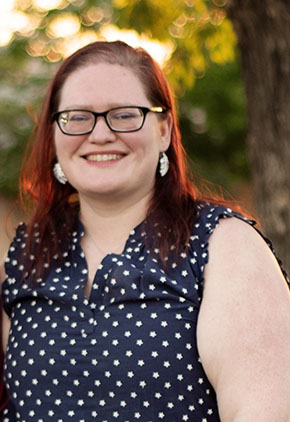 Dr. Mary Stallings smiles for a professional photo outside. She is wearing a navy top that features white polka dots.