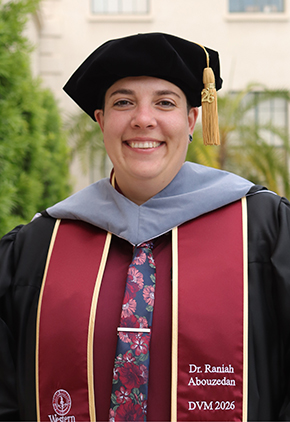 Dr. Raniah Abouzedan smiles outside on Western University's campus. She is wearing her doctoral robe and stoll with a red dress shirt and coordinating floral tie.