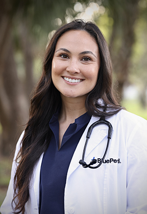 Dr. Bianca Coleman smiles outside for a professional headshot. She is wearing a navy blouse and her BluePearl whitecoat with a stethoscope around her neck.