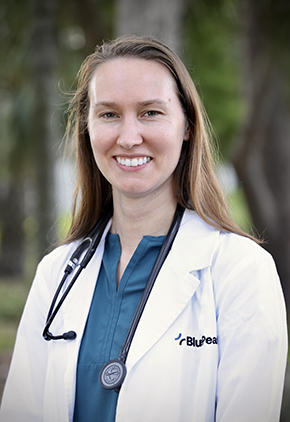 Dr. Kellie Holden smiles outside for a professional headshot. She is wearing a turquoise blouse, her BluePearl whitecoat and has a stethoscope around her neck.