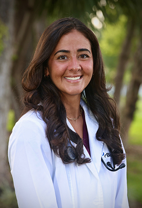 Dr. Christiana Popo smiles outside for a professional headshot. She is wearing black scrubs, her BluePearl whitecoat and has a stethoscope around he neck.