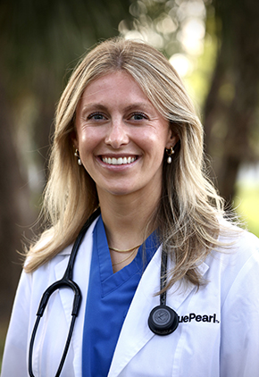 Dr. Anabell Wondrasch smiles outside for a professional headshot. She is wearing blue scrubs, her BluePearl whitecoat and has a stethoscope around her neck.