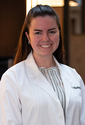Dr. Grace Malla smiles for a headshot in the lobby of BluePearl Pet Hospital. She is wearing a light green blouse and her whitecoat.