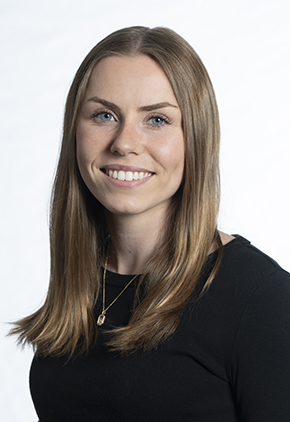 Dr. Jenna Freak smiles for a professional headshot in front of a white background. She is wearing a black top.