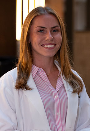 Dr. Jenna Freak smiles for a headshot in the lobby of BluePearl Pet Hospital. She is wearing a pink blouse and her whitecoat.