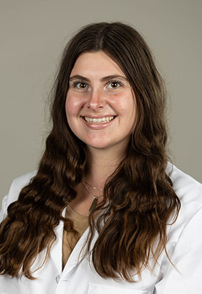 Dr. Danielle Alms smiles for a professional headshot. She is wearing her white coat.
