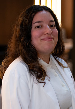Dr. Ryan Phoenix smiles for a headshot in the lobby of BluePearl Pet Hospital. She is wearing a white blouse and her whitecoat.
