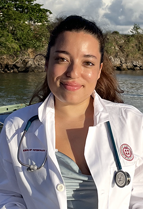 Dr. Ryan Phoenix smiles outside in Grenada. She is wearing her St. George's University whitecoat.