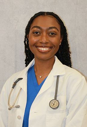 Dr. Imara Savon smiles for a professional headshot. She is wearing blue scrubs, white coat and has a stethoscope around her neck.