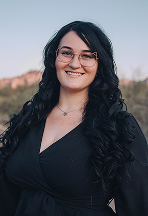 Dr. Madison Hammond smiles outside at golden hour. She is wearing a black dress.