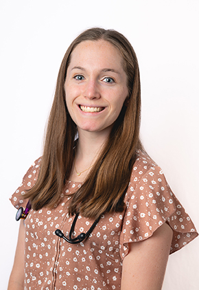 Dr. Nicole Remes smiles for a professional headshot in front of a white background. She is wearing a tan polka dot shirt and has a stethoscope around her neck.