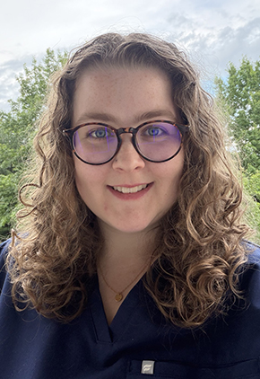 Dr. Kylie McClure smiles outside for a headshot. She is wearing dark navy scrubs.