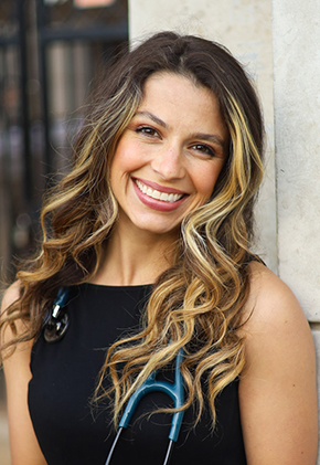 Dr. Savannah Smith smiles outside for a professional headshot. She is wearing a black dress and has a blue stethoscope around her neck.
