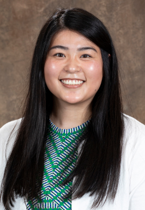 Dr. Jacqueline Tai Li Nelson smiles for a professional studio headshot. She is wearing a green blouse and white cardigan.