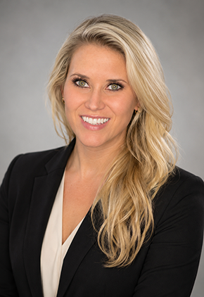 Dr. Tiana Royer smiles for a professional headshot. She is wearing a cream colored blouse and a black blazer.
