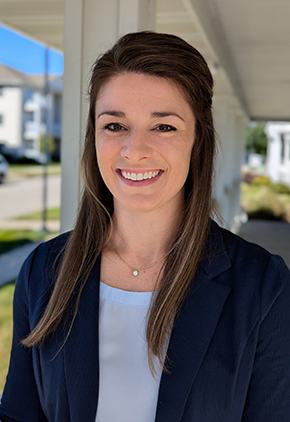 Dr. Katie Goebel smiles for a headshot outside. She is wearing a white blouse and a navy cardigan.