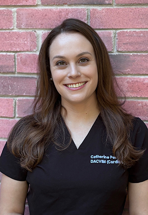 Dr. Catherine Peng smiles outside in front of a brick building. She is wearing black personalized scrubs.